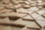 Wooden panels with a geometric pattern of raised triangles create a textured surface. The natural wood grain features warm, earthy tones.
